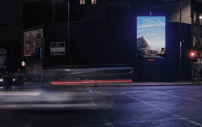 Passo billboard at night beside a For Sale hoarding