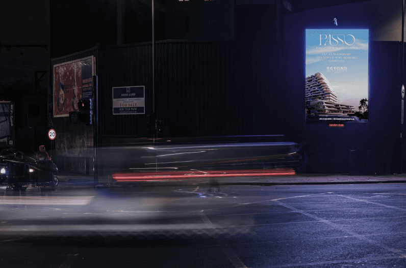 Passo billboard at night beside a For Sale hoarding