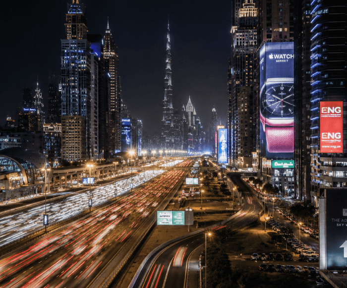 A Dubai highway at night with skyscrapers and light trails
