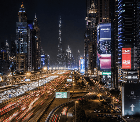 A Dubai highway at night with skyscrapers and light trails